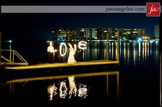 a bride and groom standing on a dock with the city lights reflected in the water