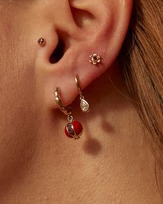 a close up of a woman's ear with three different colored earrings on it