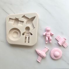 some toys are laying on a white table with pink molds next to one another