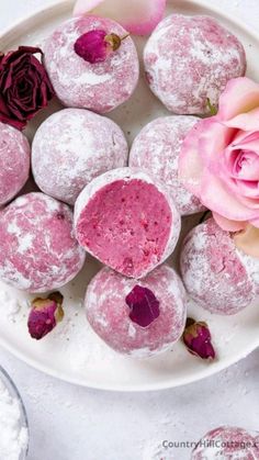 powdered doughnuts with pink icing and rose petals on a white plate