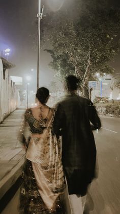 a man and woman walking down the street at night