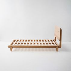 a wooden bed frame sitting on top of a white floor in front of a wall