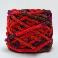 a spool of yarn that is red, orange and brown with some purple on it