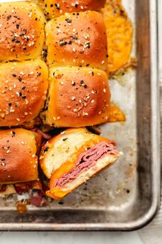 several sliders with meat and cheese on them in a baking pan, ready to be eaten