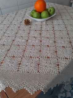 a bowl of fruit sitting on top of a table next to apples and oranges