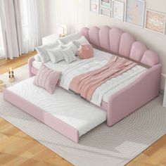 a pink and white bed in a room with pictures on the wall behind it,