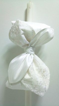 two white napkins tied to a pole with lace on them and one has a bow at the top