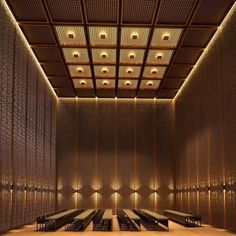 an empty room with tables and benches in the center, lit by lights from above