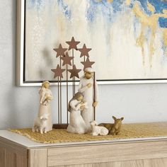 three small figurines sitting on top of a wooden table next to a painting