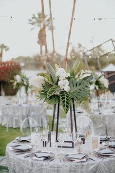 a table is set up with white flowers and greenery for an elegant wedding reception