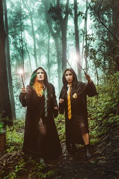 two people dressed in harry potter costumes holding wands and pointing to the sky with their hands