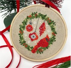 a cross stitch christmas ornament hanging from a tree