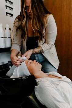 a woman is getting her hair done in a salon while another person watches from the side