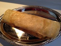 a silver plate with a large piece of bread on it and a spoon next to it