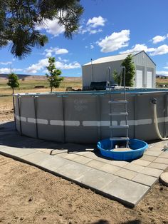 an above ground swimming pool in the middle of a dirt field with a ladder up to it