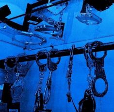 several pairs of handcuffs hanging from hooks in a blue room