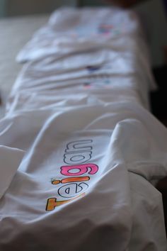 an unmade bed with white sheets and colorful logos on it