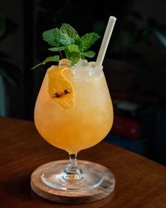 a glass filled with lemonade sitting on top of a wooden table next to a plant