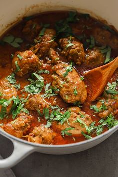 meatballs and tomato sauce in a pot with a wooden spoon