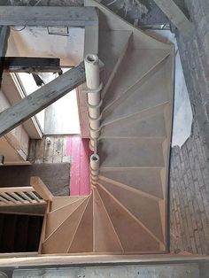 an overhead view of a stair case in a building with red door and wooden railings