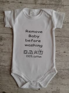 a white baby bodysuit that says remove baby before washing 100 % cotton on it