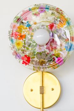 a glass plate with flowers on it is mounted to a wall by a metal hook