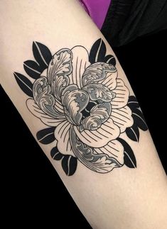 a woman's arm with a black and white tattoo design on the left forearm