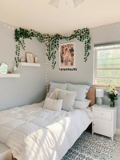 a white bed sitting in a bedroom next to a window with green vines on it