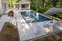 an outdoor pool with lounge chairs and umbrellas next to the swimming pool is surrounded by greenery