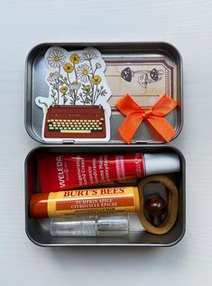 two tins filled with different items such as lipstick, lip balm and an orange bow