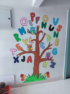 a child's room wall decorated with colorful letters and an owl on a tree