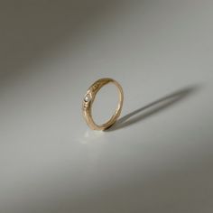 a gold ring with a single diamond on the top and bottom, sitting on a white surface