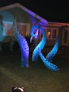 a dog laying on the ground in front of a house with blue and purple lights