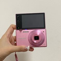 a person holding up a pink camera to take a picture with it's flash drive