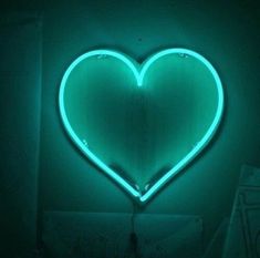 a heart shaped neon sign hanging from the side of a wall