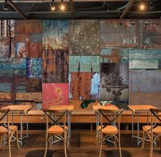 a room with several tables and chairs in front of a wall that has many different colored tiles on it