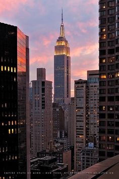 the empire building is lit up at night in new york city, ny with pink clouds