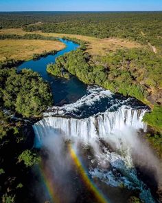 an aerial view of a waterfall with a rainbow in the middle and trees surrounding it