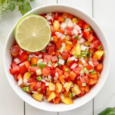 a white bowl filled with chopped up vegetables and a lime wedge on top of it