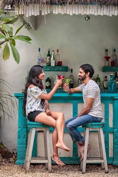 a man and woman sitting at a bar with drinks in their hands, one holding a flower