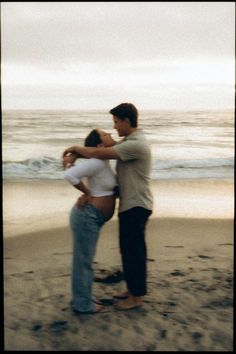 a man and woman kissing on the beach