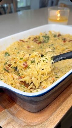 a casserole dish with noodles and vegetables in it on a wooden cutting board