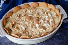 a casserole dish with crackers in it on a blue cloth next to a spoon