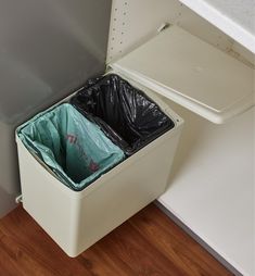 an open white trash can with a black plastic bag in it's bottom compartment