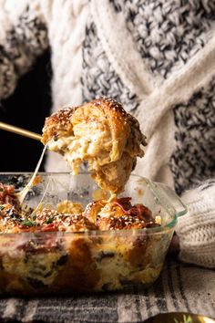 a person is dipping something into a casserole in a glass dish with a wooden spoon