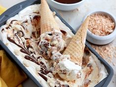 two scoops of ice cream with chocolate sauce and nuts in a pan next to bananas