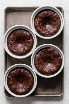 four chocolate cupcakes sitting on top of a pan