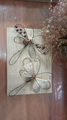 two dragonflys are sitting on a piece of cloth next to some dried flowers