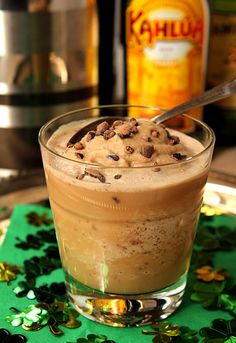 a drink in a glass with chocolate chips on the rim and shamrocks around it