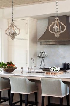 a kitchen island with four stools in front of it and a range hood above it